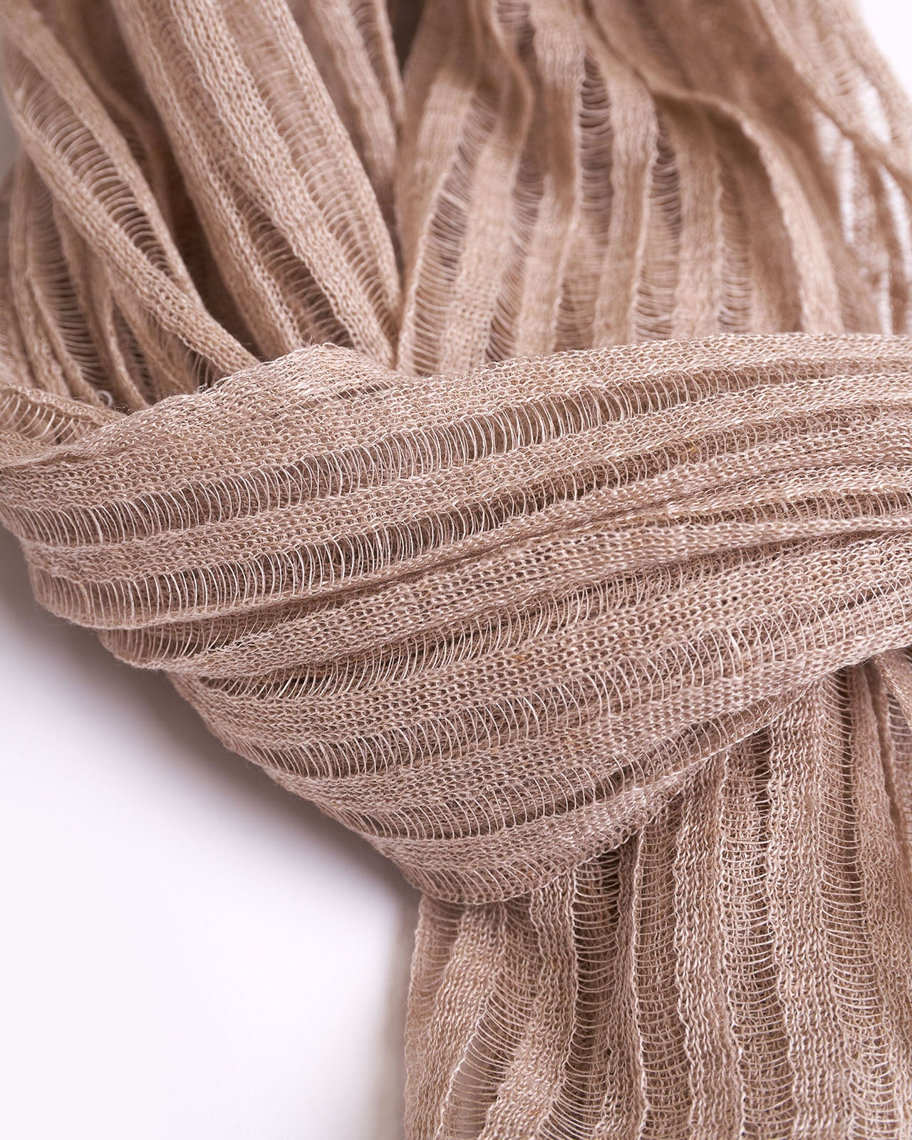 High-quality image of a neatly folded natural linen scarf in a neutral beige color, showcasing its textured weave. This elegant scarf is perfect for adding a touch of sophistication to any wardrobe, ideal for both casual and formal occasions. Its simple yet stylish design and versatile color make it an essential accessory for fashion-forward individuals.