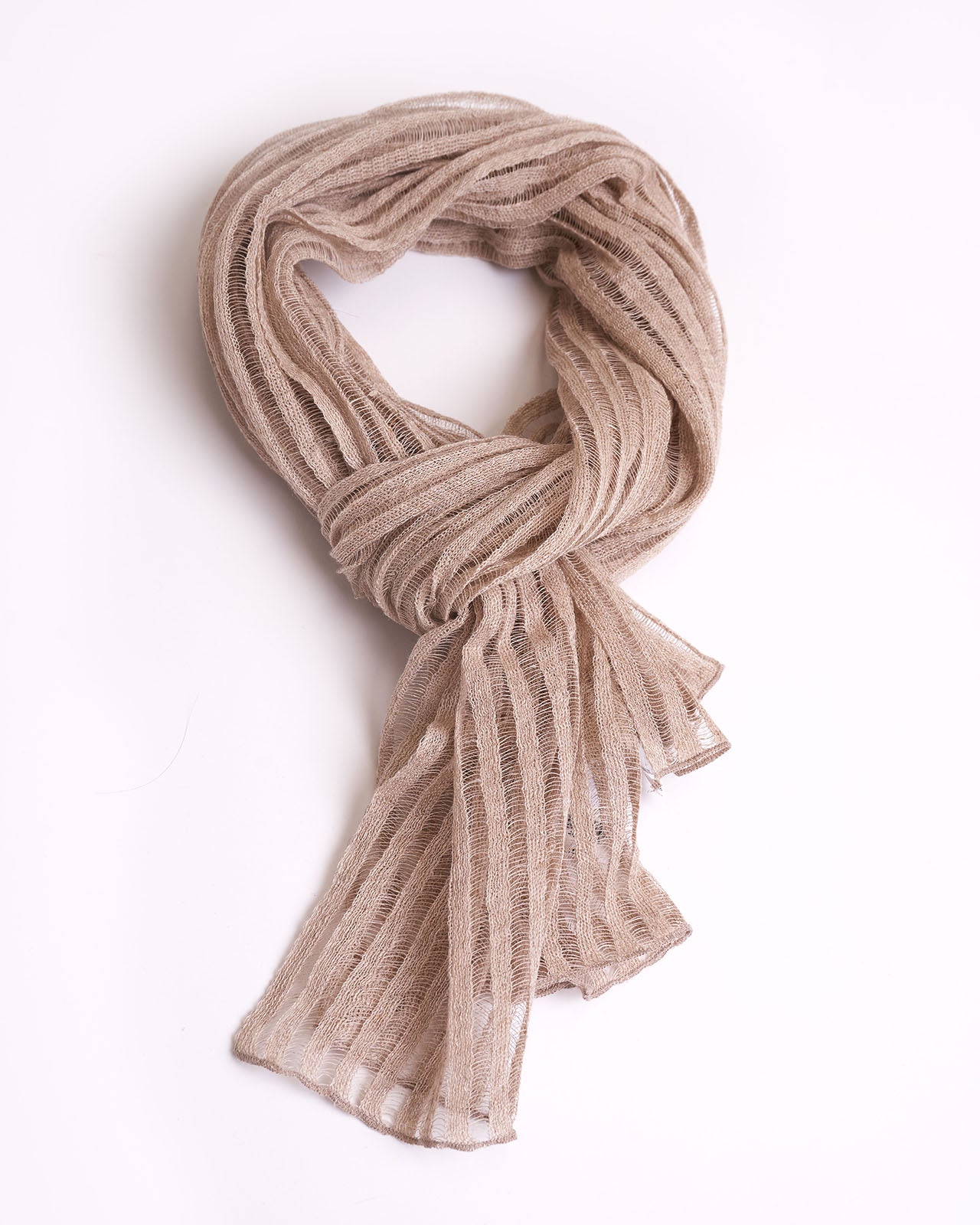 High-quality image of a neatly folded natural linen scarf in a neutral beige color, showcasing its textured weave. This elegant scarf is perfect for adding a touch of sophistication to any wardrobe, ideal for both casual and formal occasions. Its simple yet stylish design and versatile color make it an essential accessory for fashion-forward individuals.